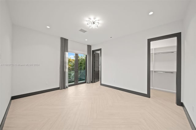 unfurnished bedroom with access to exterior, a closet, light parquet flooring, and a spacious closet