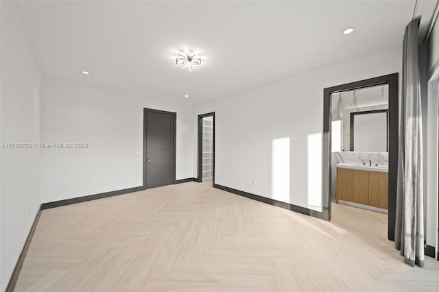 unfurnished bedroom featuring ensuite bathroom and light parquet flooring