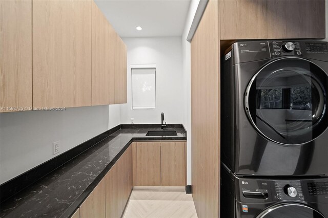 washroom featuring stacked washer and clothes dryer, sink, light tile flooring, and cabinets