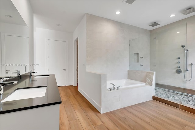 bathroom featuring double vanity, wood-type flooring, and plus walk in shower