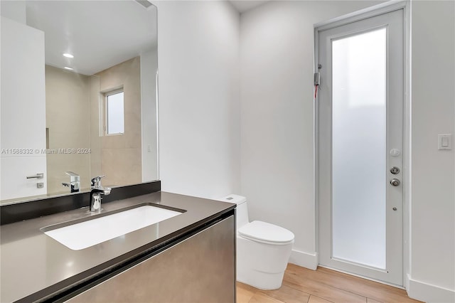 bathroom with vanity, toilet, and hardwood / wood-style floors