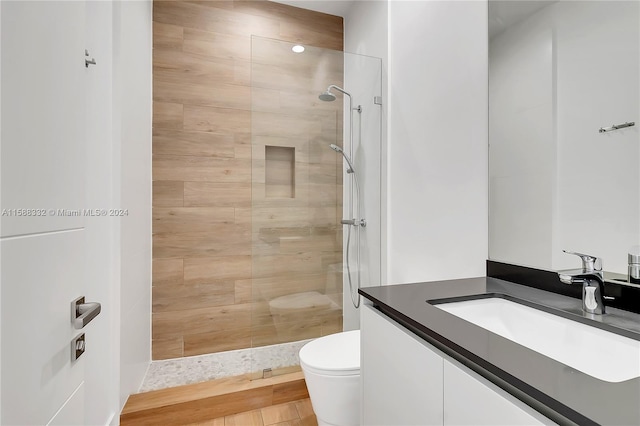 bathroom featuring a tile shower, toilet, and vanity with extensive cabinet space