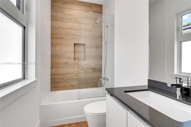 full bathroom with toilet, wood-type flooring, vanity, and tiled shower / bath