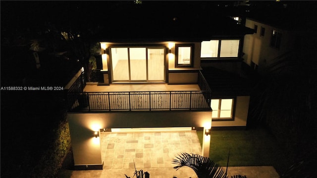 back house at twilight featuring a balcony