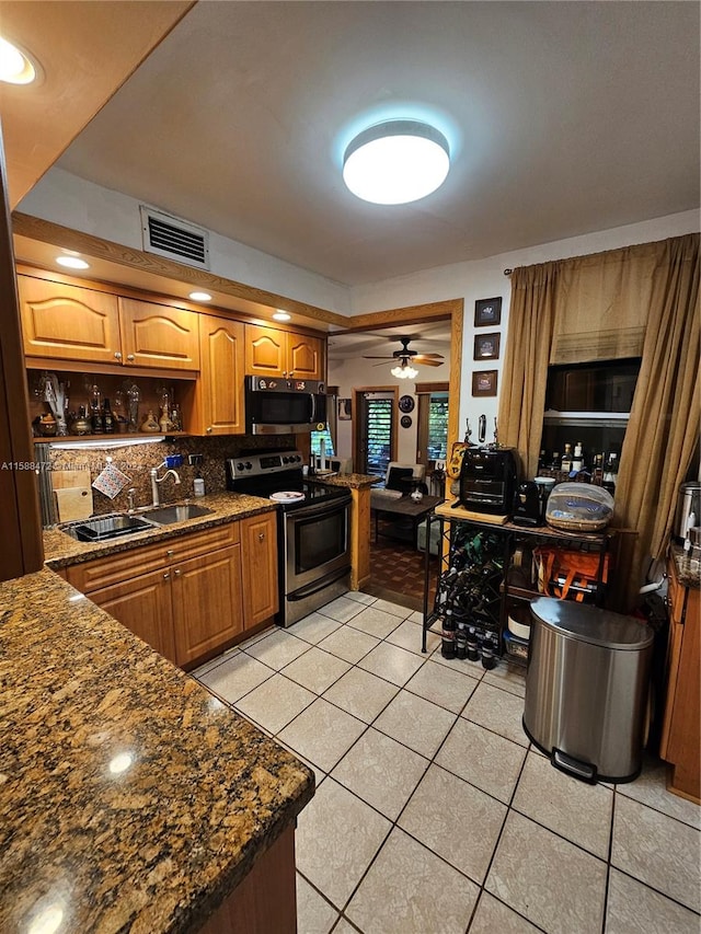 kitchen with dark stone counters, ceiling fan, stainless steel appliances, light tile flooring, and backsplash