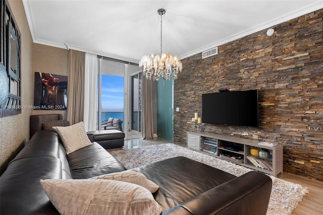 living room featuring hardwood / wood-style floors, a chandelier, a water view, and crown molding