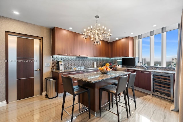 kitchen featuring a center island, dark stone countertops, backsplash, wine cooler, and a breakfast bar