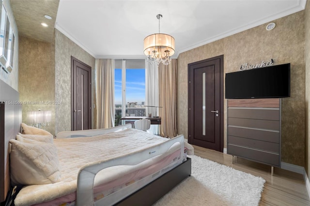 bedroom with light hardwood / wood-style floors, crown molding, and a chandelier