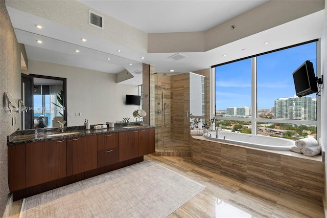 bathroom featuring large vanity, separate shower and tub, and dual sinks