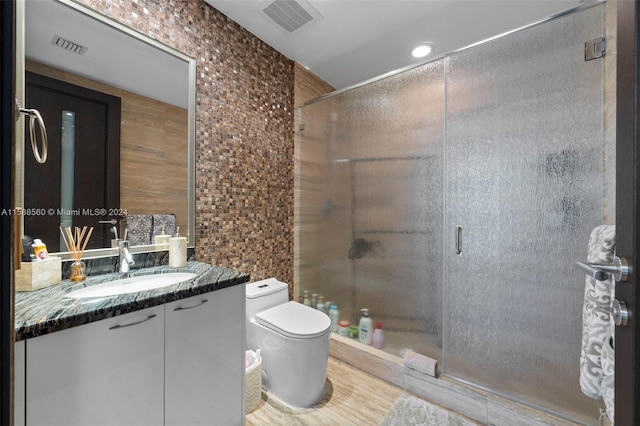 bathroom featuring walk in shower, vanity, toilet, and tile walls