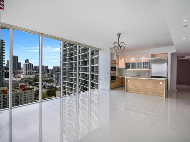 kitchen featuring floor to ceiling windows, a chandelier, appliances with stainless steel finishes, and light tile patterned floors