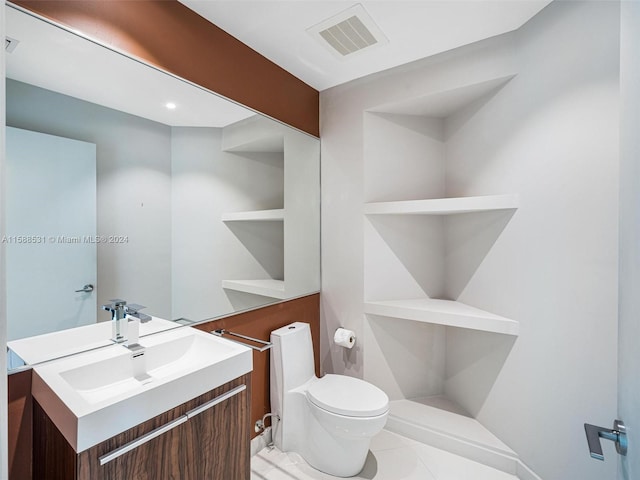 bathroom with toilet, vanity, and tile patterned flooring