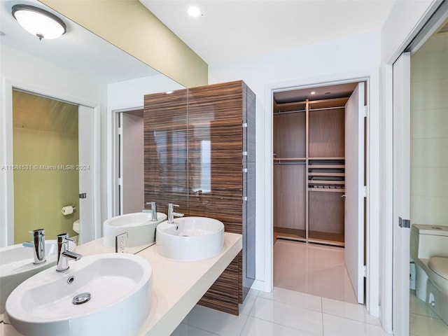 bathroom with toilet, double sink, and tile patterned flooring