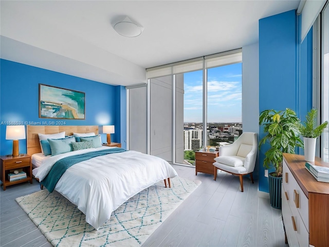 bedroom featuring a wall of windows and light wood-type flooring