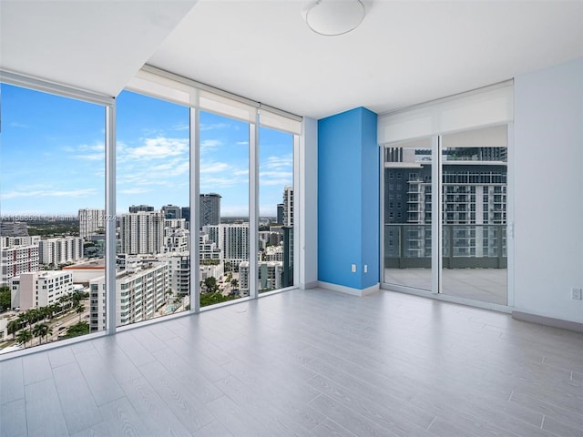 empty room with a wall of windows and hardwood / wood-style floors