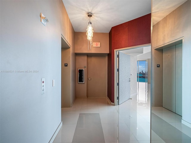 hallway with a notable chandelier, elevator, and light tile patterned floors