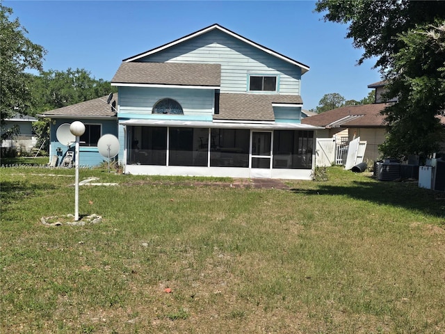 rear view of house featuring a yard, a sunroom, and central AC unit