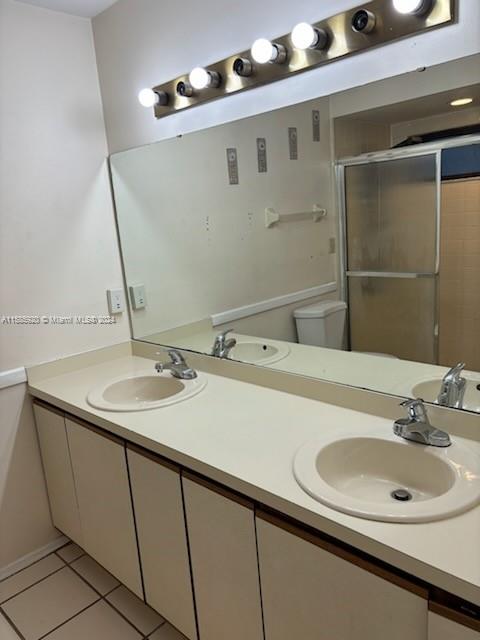 bathroom featuring toilet, tile patterned floors, and double vanity