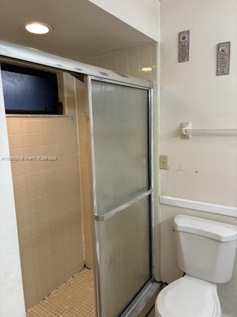 bathroom featuring a shower with shower door and toilet