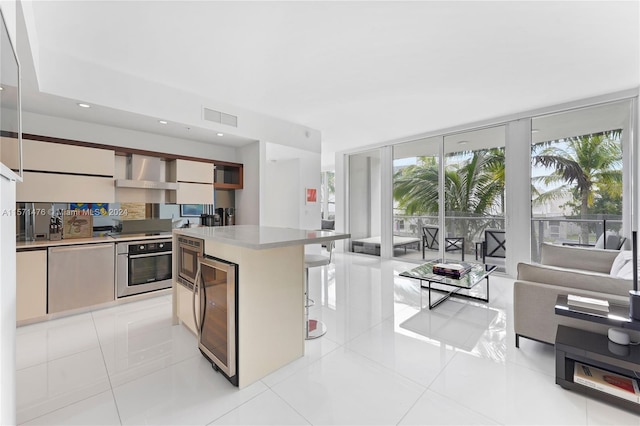 kitchen with wall chimney range hood, appliances with stainless steel finishes, beverage cooler, backsplash, and light tile floors