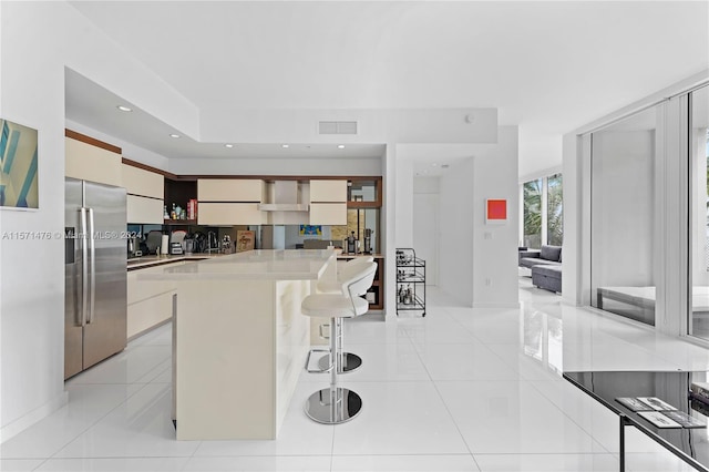 kitchen featuring a center island, a kitchen breakfast bar, stainless steel fridge with ice dispenser, and light tile floors