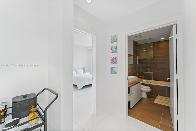 full bathroom with tiled shower / bath, vanity, toilet, and tile floors