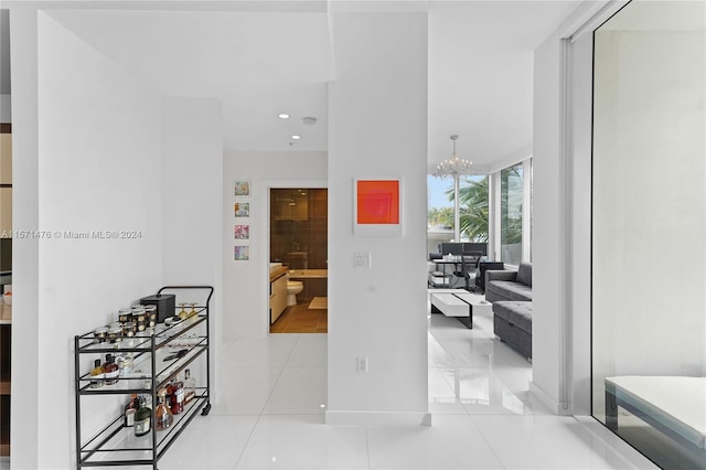 corridor with a notable chandelier, wine cooler, and light tile floors