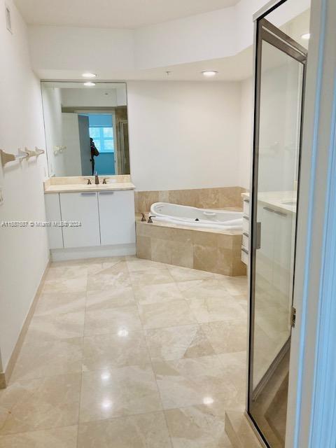 bathroom featuring tile flooring, vanity, and plus walk in shower