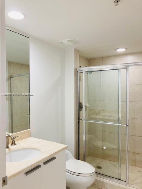 bathroom featuring a shower with shower door, vanity, and toilet