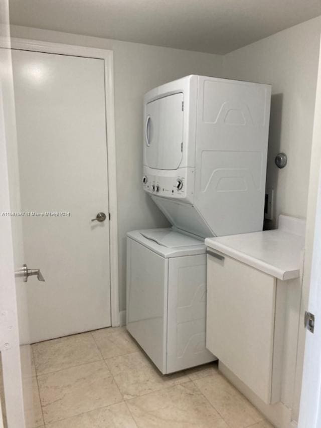 laundry room featuring stacked washer and clothes dryer and light tile floors