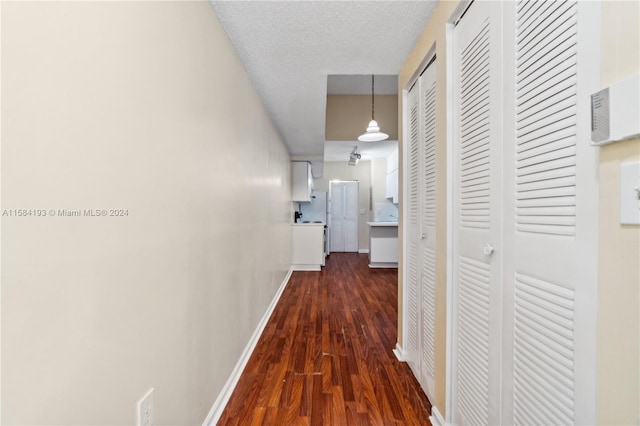 hall with dark wood-type flooring and a textured ceiling