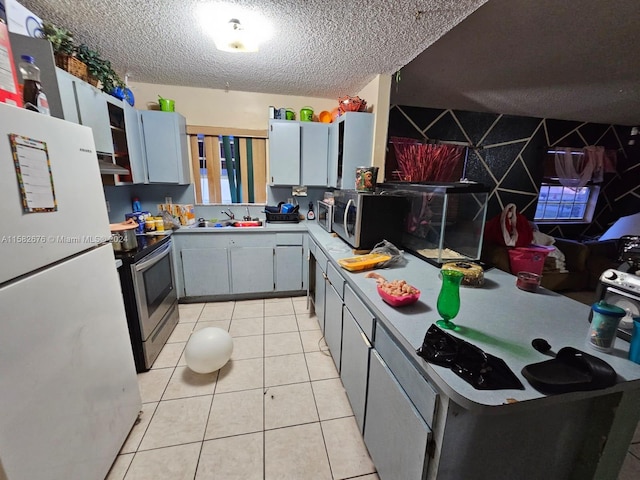 kitchen featuring light tile patterned flooring, sink, a textured ceiling, gray cabinets, and appliances with stainless steel finishes