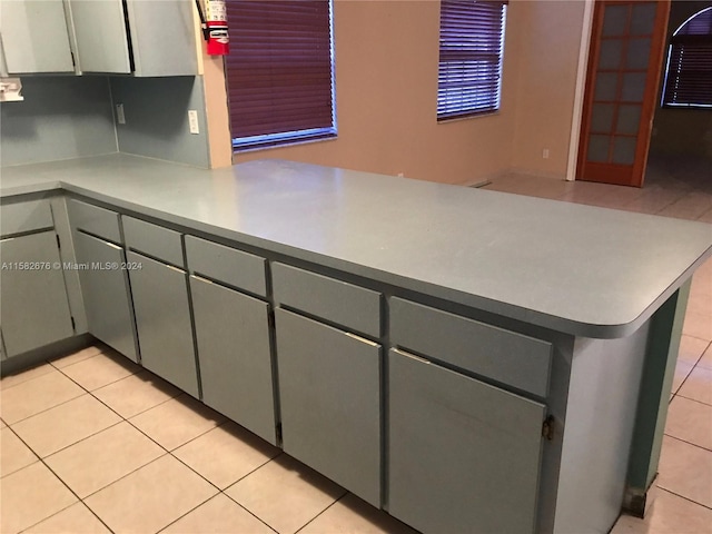 kitchen with light tile patterned floors, gray cabinets, and kitchen peninsula