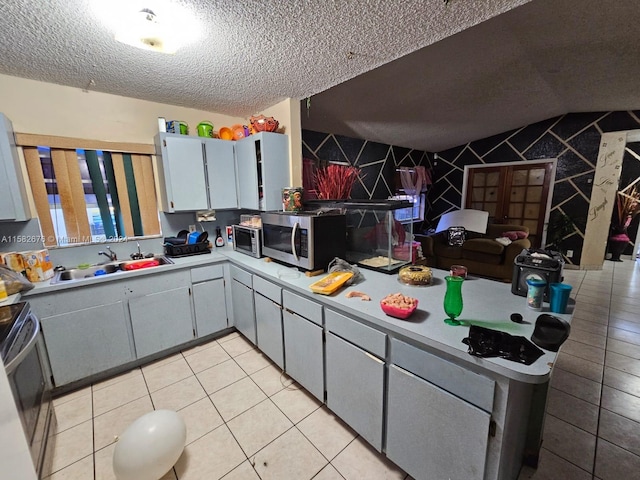 kitchen with light tile patterned flooring, sink, a textured ceiling, gray cabinets, and stainless steel appliances