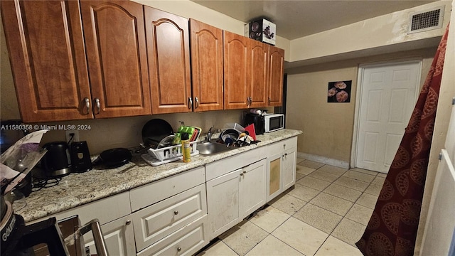 kitchen with sink, light tile patterned floors, and light stone counters