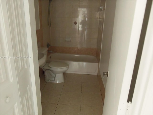 bathroom with tile floors, toilet, and tiled shower / bath