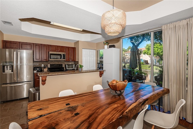 dining room featuring a raised ceiling and dark tile floors