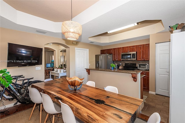 dining area with a raised ceiling and dark tile floors