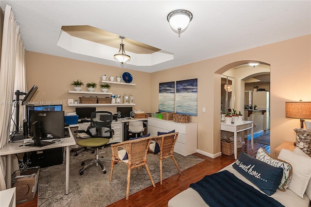 home office with a raised ceiling and wood-type flooring