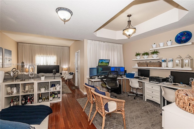 office area with dark hardwood / wood-style flooring, a tray ceiling, and a textured ceiling