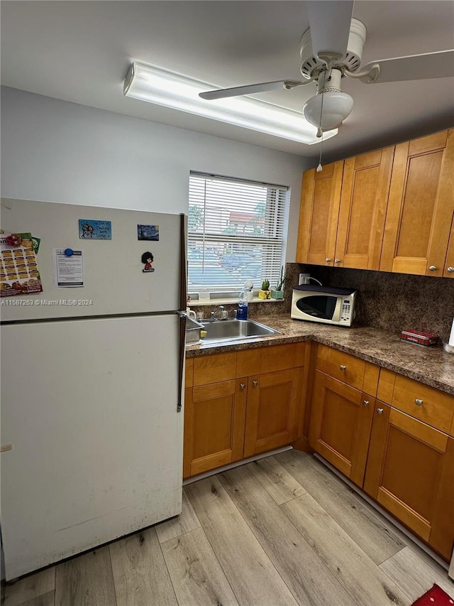 kitchen with backsplash, ceiling fan, light wood-type flooring, sink, and white appliances