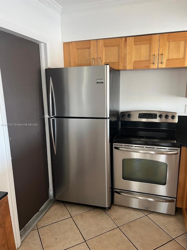 kitchen featuring stainless steel appliances, ornamental molding, and light tile floors