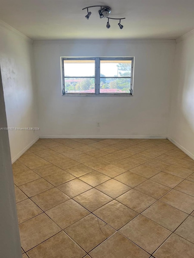 tiled empty room with ornamental molding and rail lighting