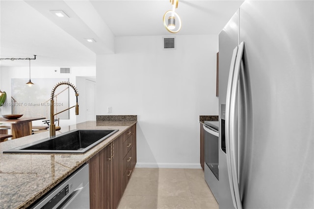 kitchen featuring stainless steel appliances, pendant lighting, light stone counters, light tile floors, and sink