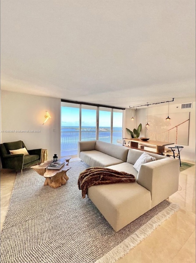 tiled living room featuring expansive windows, a water view, and rail lighting