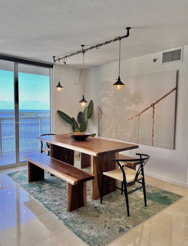 tiled dining space featuring floor to ceiling windows, a textured ceiling, and a water view