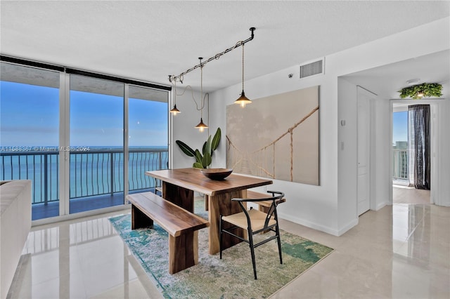 tiled dining area featuring a water view, a textured ceiling, and rail lighting