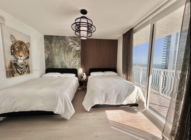 bedroom featuring a notable chandelier, hardwood / wood-style flooring, and access to exterior