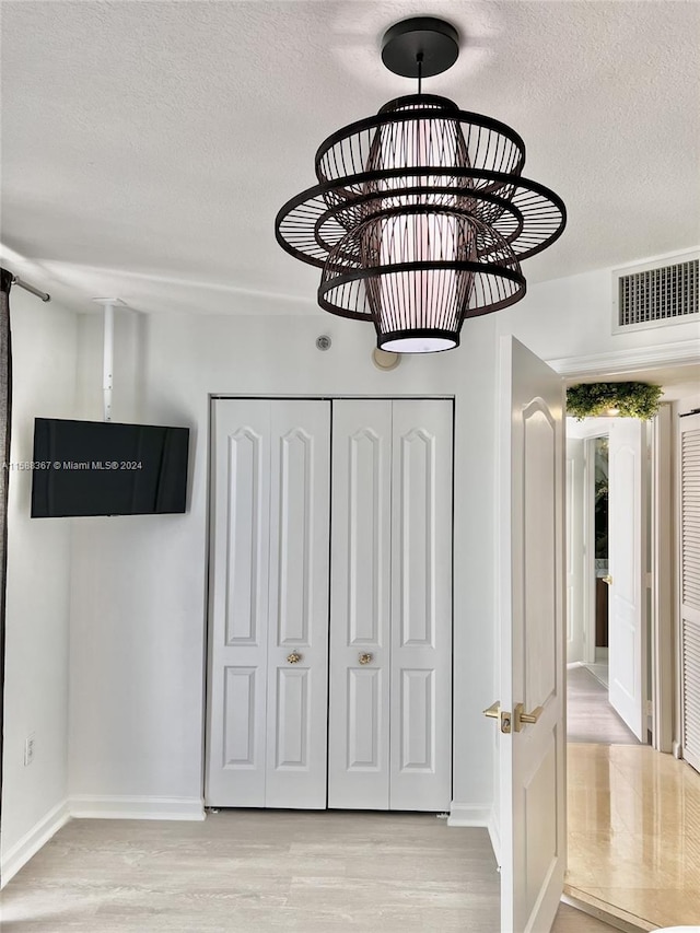 unfurnished bedroom with a closet, a textured ceiling, and light wood-type flooring