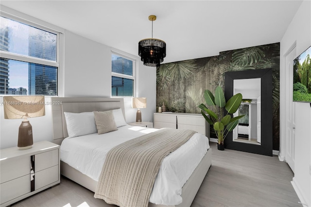 bedroom with an inviting chandelier, light wood-type flooring, and multiple windows